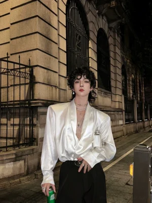 White satin deep V-neck shirt with relaxed draped fit styled with high-waisted black trousers on a vintage street