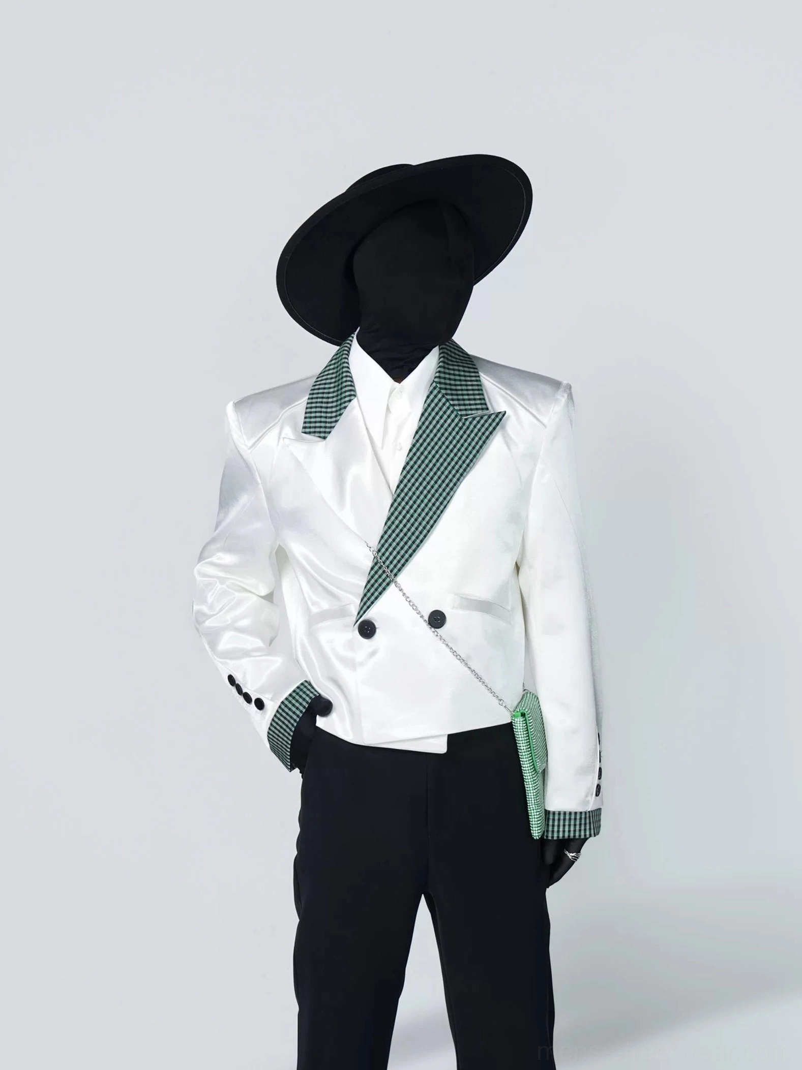 Front view of a structured white satin-finish houndstooth tuxedo blazer with peak lapels, double-breasted buttons, and black flared trousers