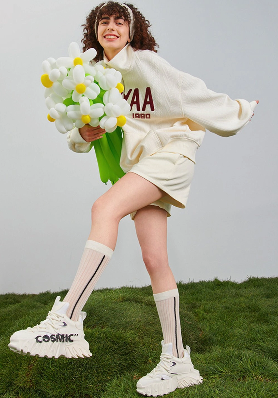 White sculpted platform derby sneakers styled with a cream sweatshirt and shorts outdoors, featuring Cosmic side graphics and a rugged chunky outsole