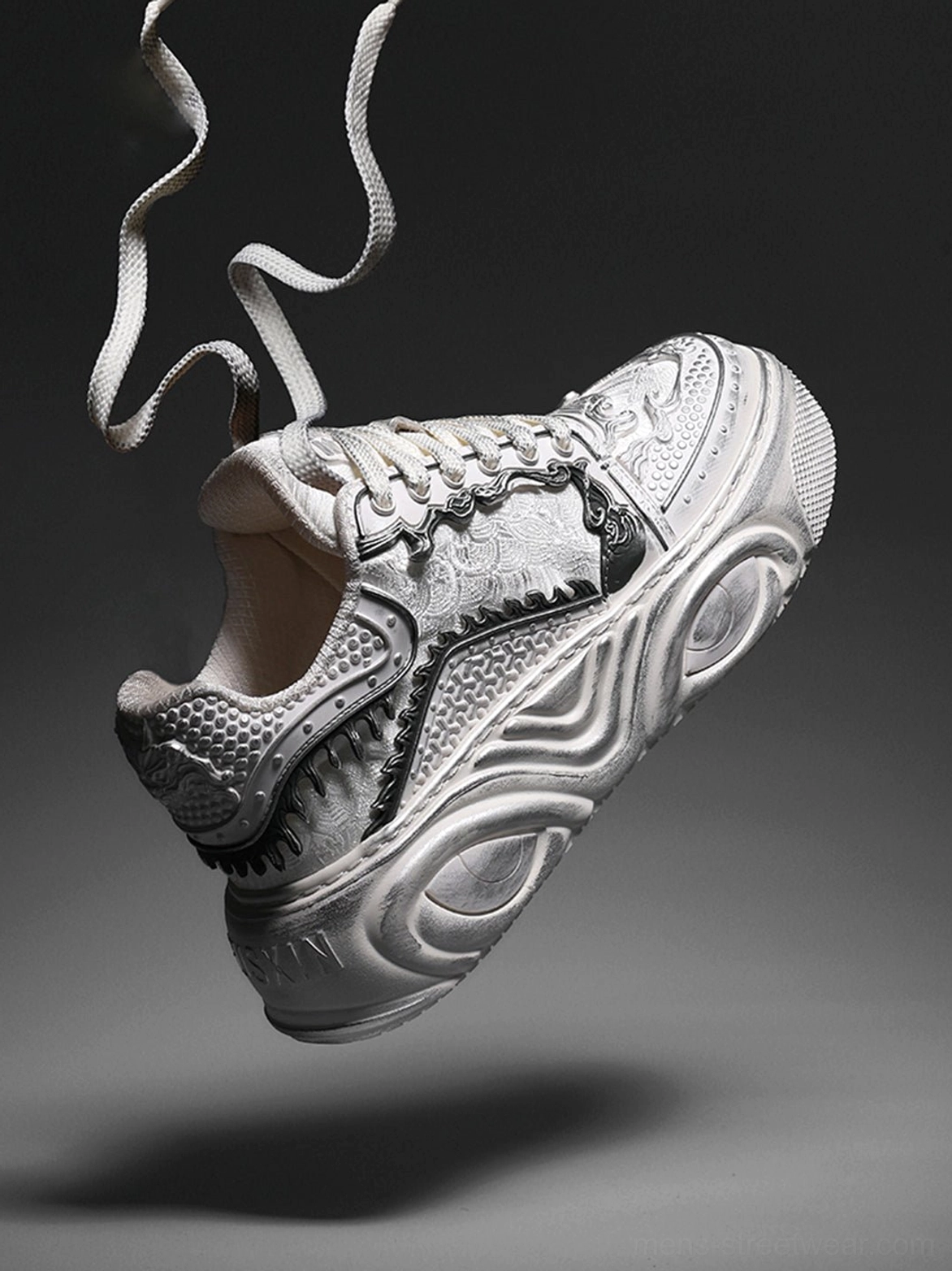 Angled close-up of a white sculpted platform sneaker with loose flat laces, textured synthetic textile upper, and chunky wave sole