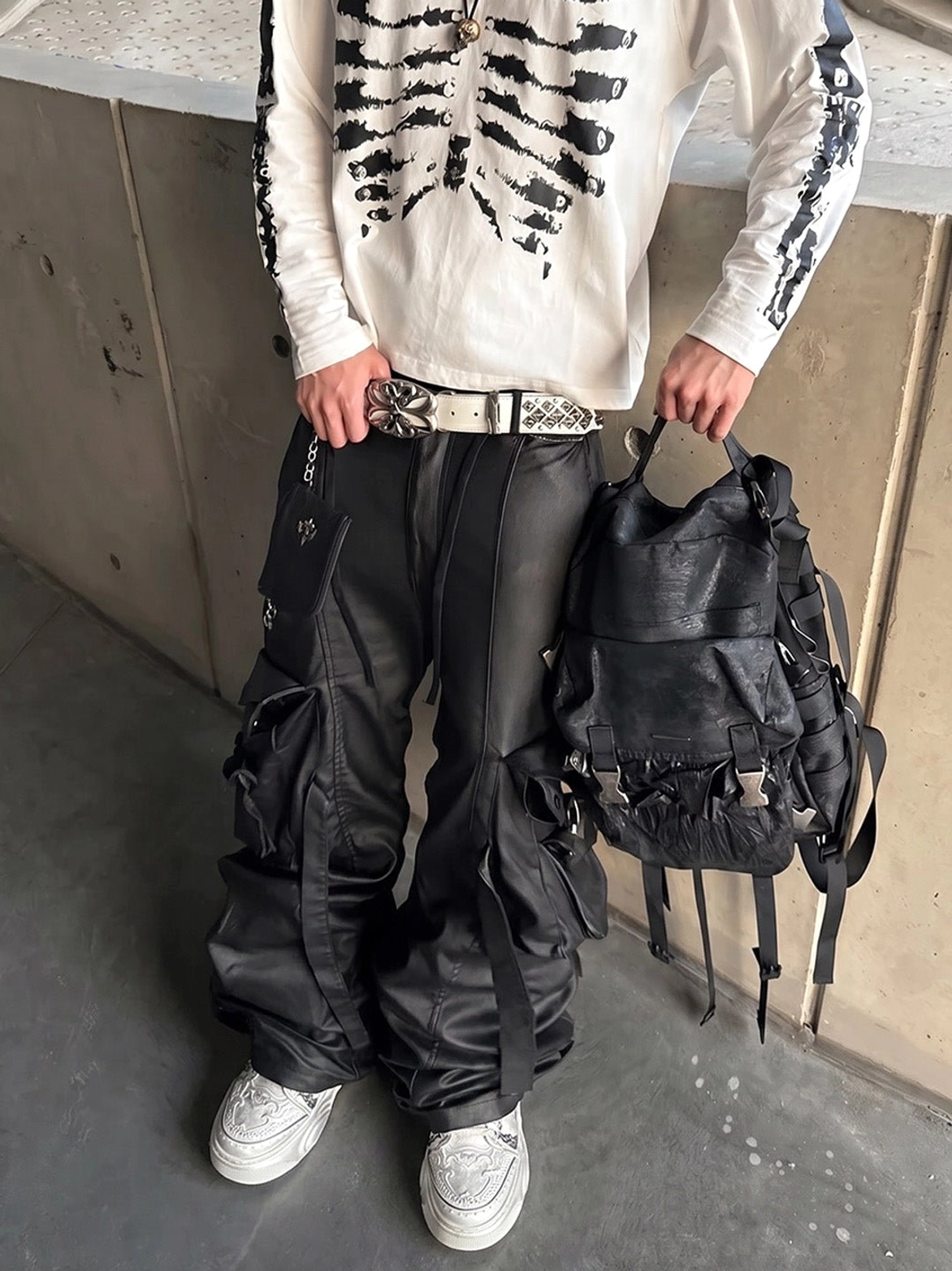 Front low-angle view of a male streetwear outfit styled with white sculpted platform sneakers and black cargo trousers
