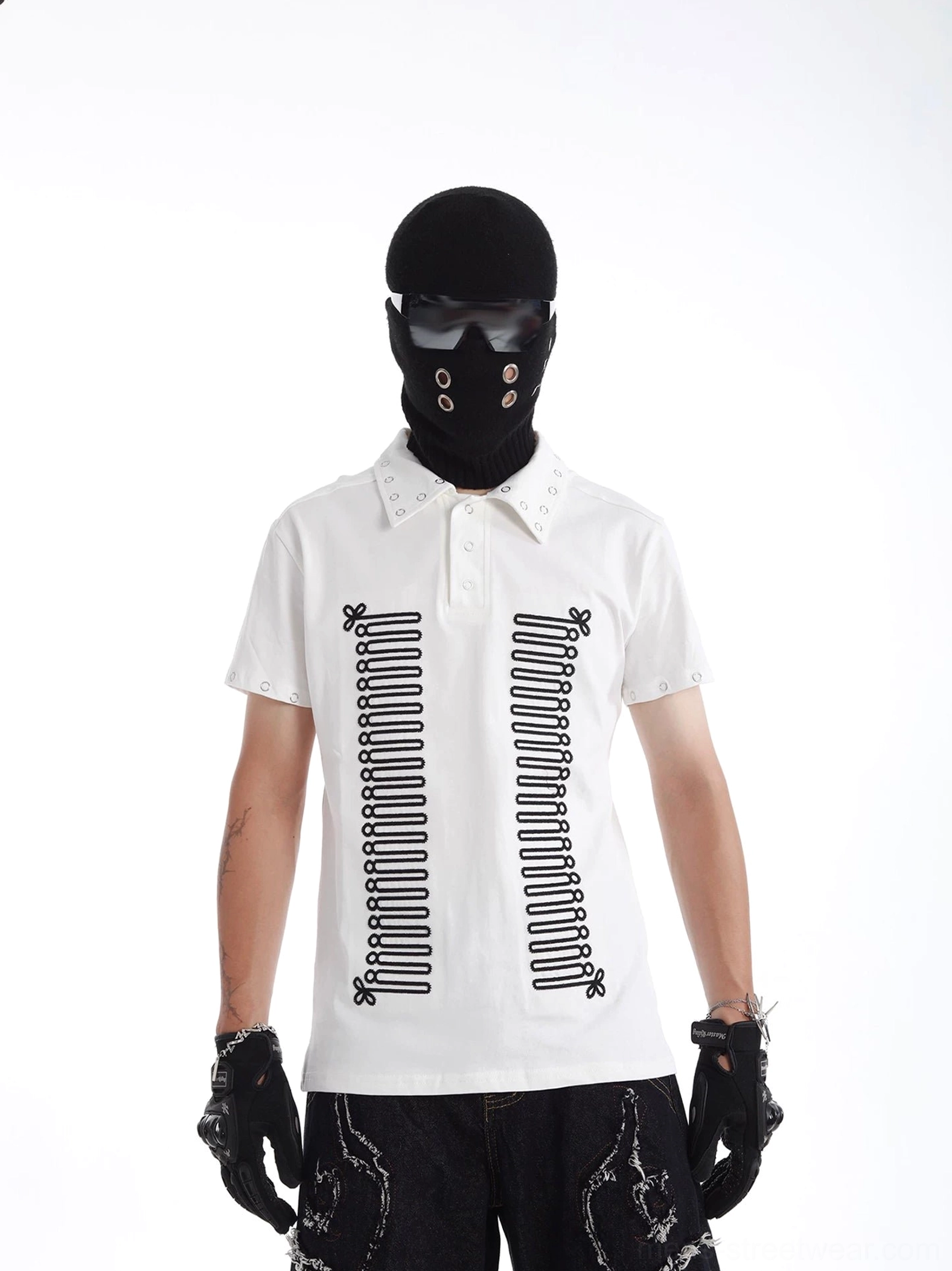 White skeleton graphic polo shirt with black symmetrical spine artwork, metal eyelet collar and sleeve details, styled with ripped black denim