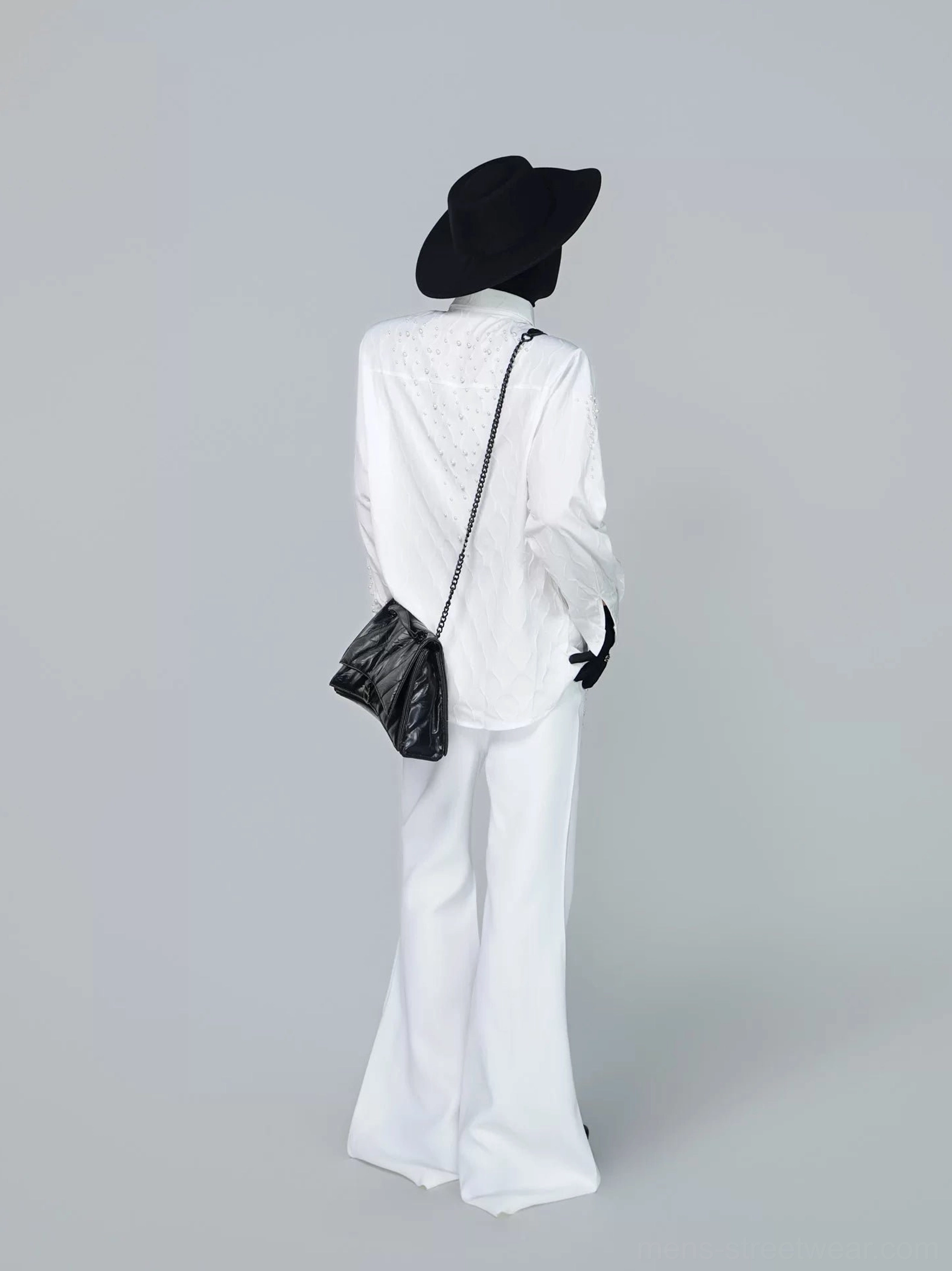 Back view of coordinated white embellished shirt and flared trousers showing matching starfall details with a black quilted chain crossbody bag