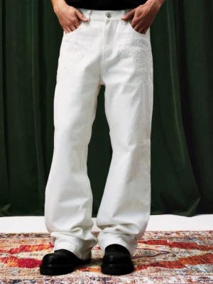 Front full body view of white tonal embroidered wide leg streetwear jeans with relaxed stacked hem