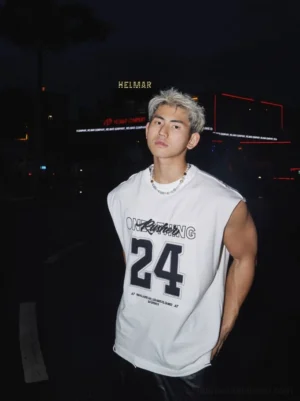 White varsity 24 oversized sleeveless muscle tee front view styled in a night city streetwear setting