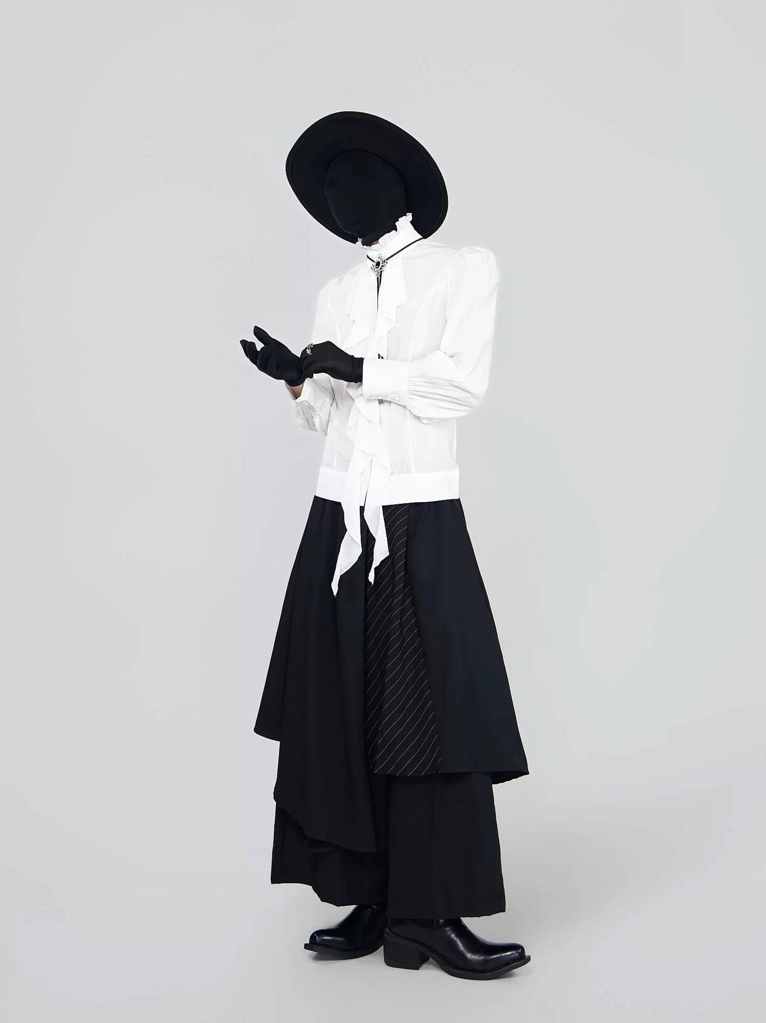 Side three quarter view of a white Victorian ruffle blouse with fitted waist and puff sleeves paired with a black high low asymmetric skirt and leather boots