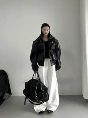 Female model styling oversized white wide-leg wave pants with a black cropped top leather puffer jacket and large tote bag