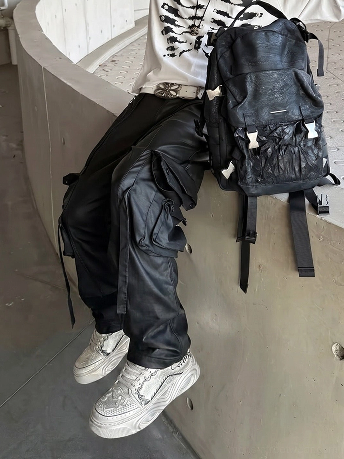 Seated male model wearing distressed white Wukong-inspired platform sneakers in a contemporary urban streetwear setting
