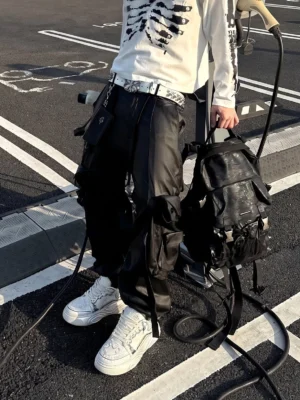 Male model wearing white Wukong-inspired platform sneakers with black cargo pants and a skeleton graphic streetwear top outdoors