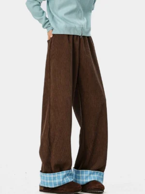 Side rear view of deep brown wide-leg corduroy trousers with blue plaid turn-up cuffs styled with a cropped light blue knit top and platform loafers