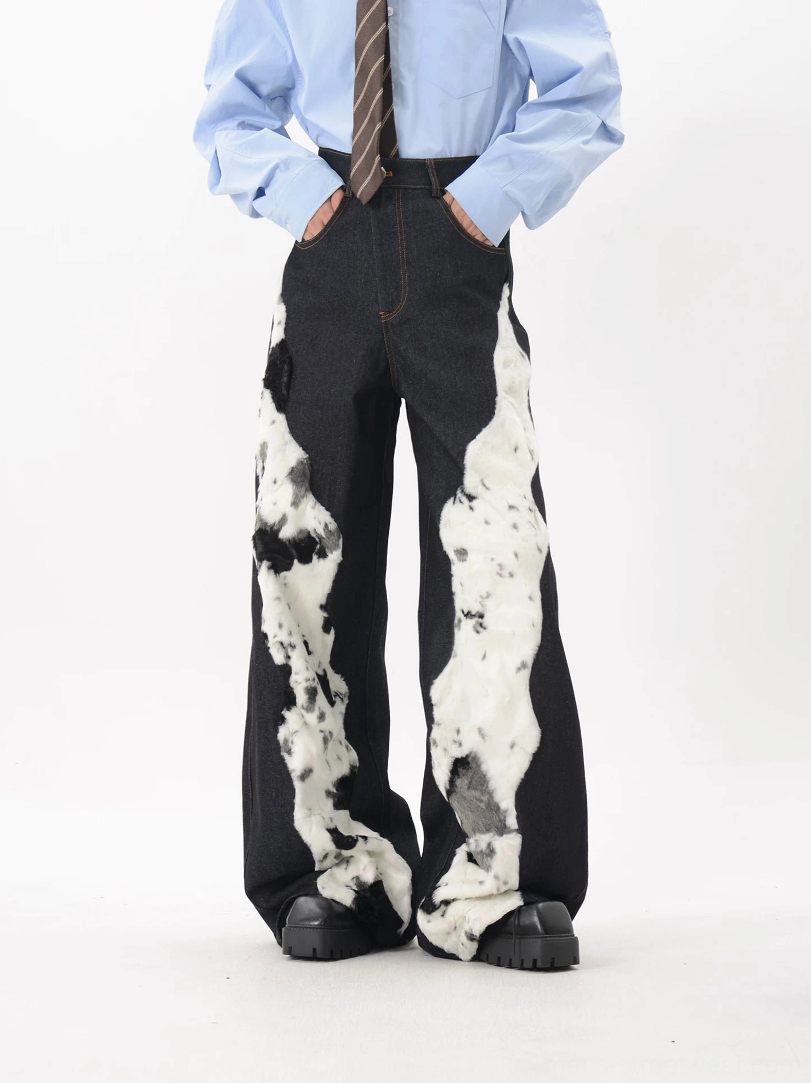 Front view of wide leg dark denim trousers with cow pattern faux fur patches and detailed contrast topstitching