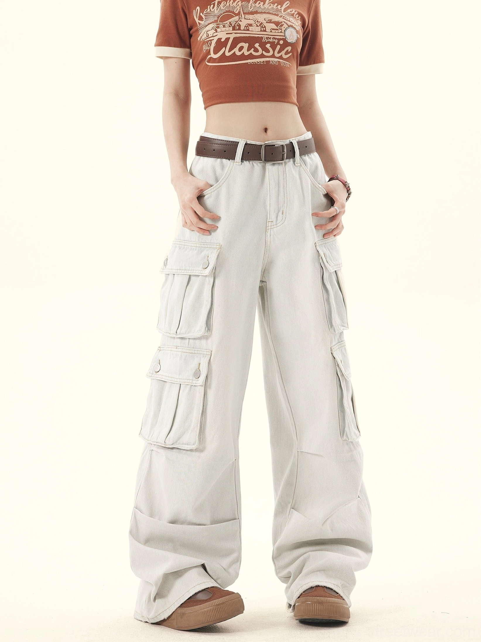 Three-quarter left view of relaxed wide-leg denim cargo pants showing stacked side utility pockets