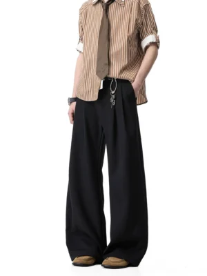 Black wide-leg draped trousers with front pleats and waist hanging details styled as tailored Korean streetwear on a male model