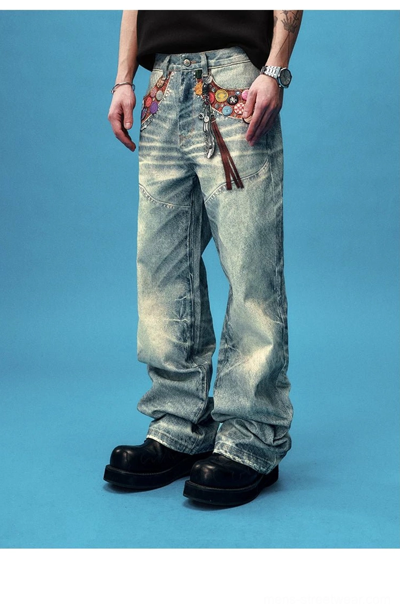 Low angle front view of light blue wide leg jeans with colorful waistband badges and hanging tassel chain
