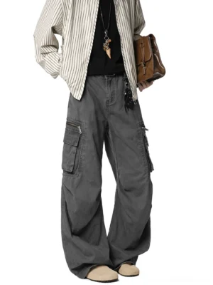 Dark charcoal gray wide-leg cargo pants on a male model with a leather shoulder bag and layered utility pockets