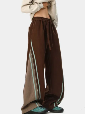 Dark brown wide-leg varsity track pants with light cyan and off-white side stripes, elastic drawstring waist, and relaxed Korean streetwear styling
