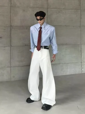 Male model wearing white wide-leg wave pants with a structured tailored silhouette in a minimalist concrete studio