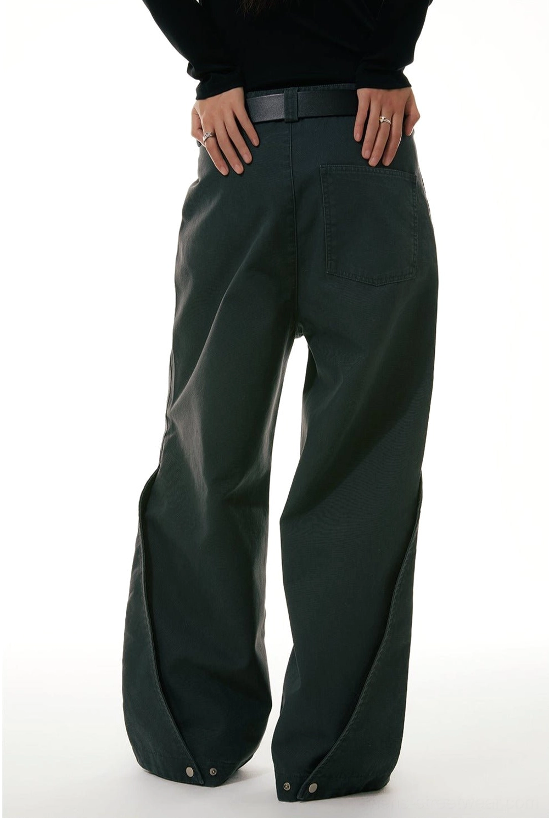 Low-angle back view of wide-leg workwear denim jeans showing rear pockets, leather belt styling, and adjustable snap cuff details