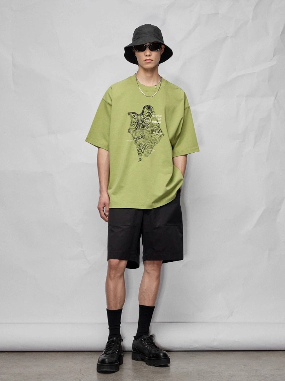 Relaxed black knee-length streetwear shorts styled with an oversized animal graphic tee, bucket hat, and sunglasses