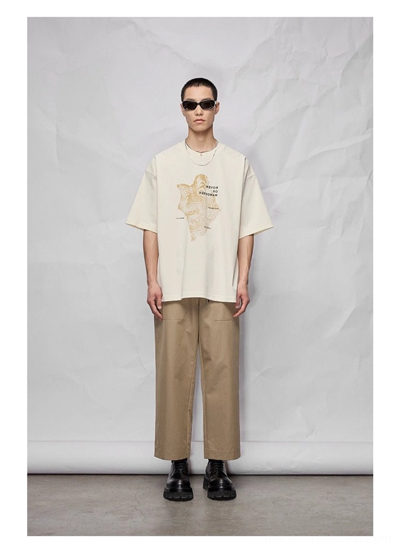 Full-body streetwear outfit featuring khaki wide cropped pants, a white graphic oversized tee, sunglasses, and casual shoes