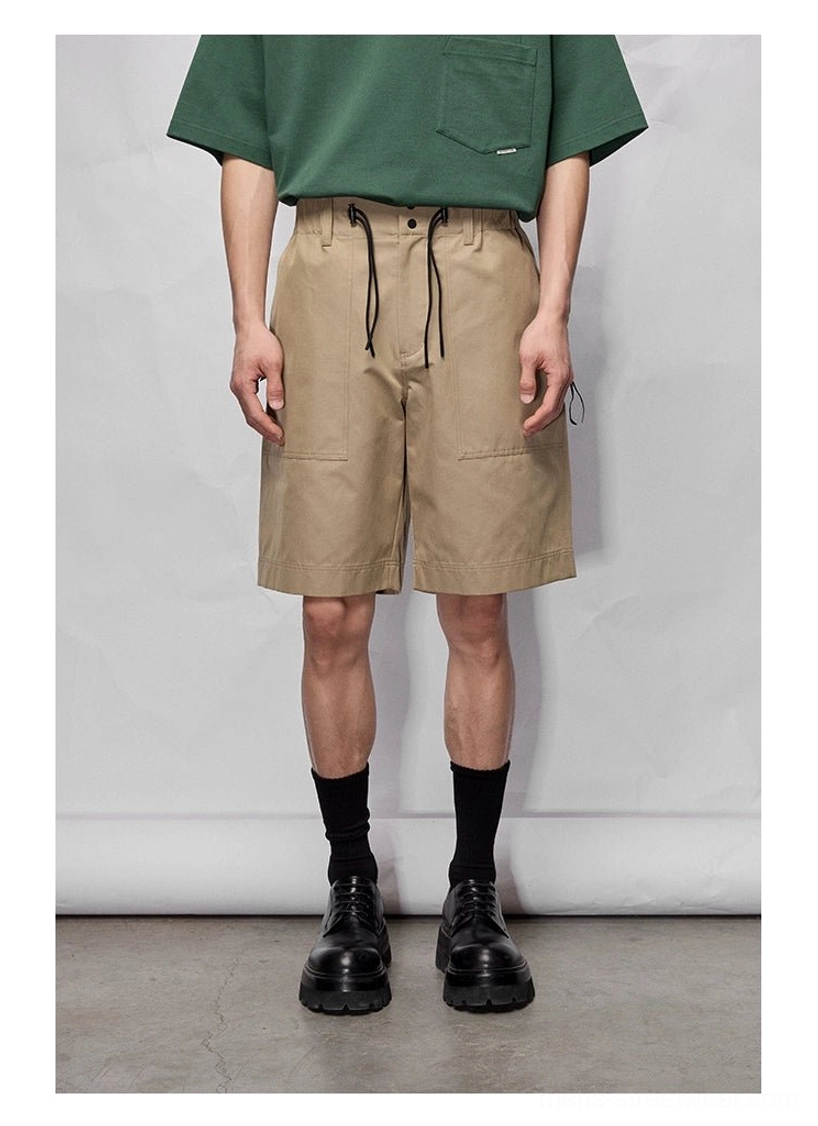 Close lower-body view of khaki wide relaxed knee-length streetwear shorts with adjustable drawstring waist and patch pockets