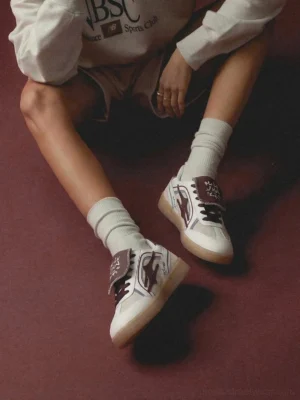 Wine red and white retro streetwear sneakers viewed from above on a model wearing crew socks and a cropped casual outfit