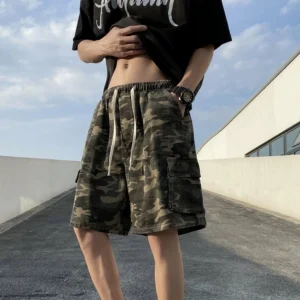 Men's relaxed-fit woodland camouflage cargo shorts styled outdoors in a front three-quarter rooftop streetwear outfit