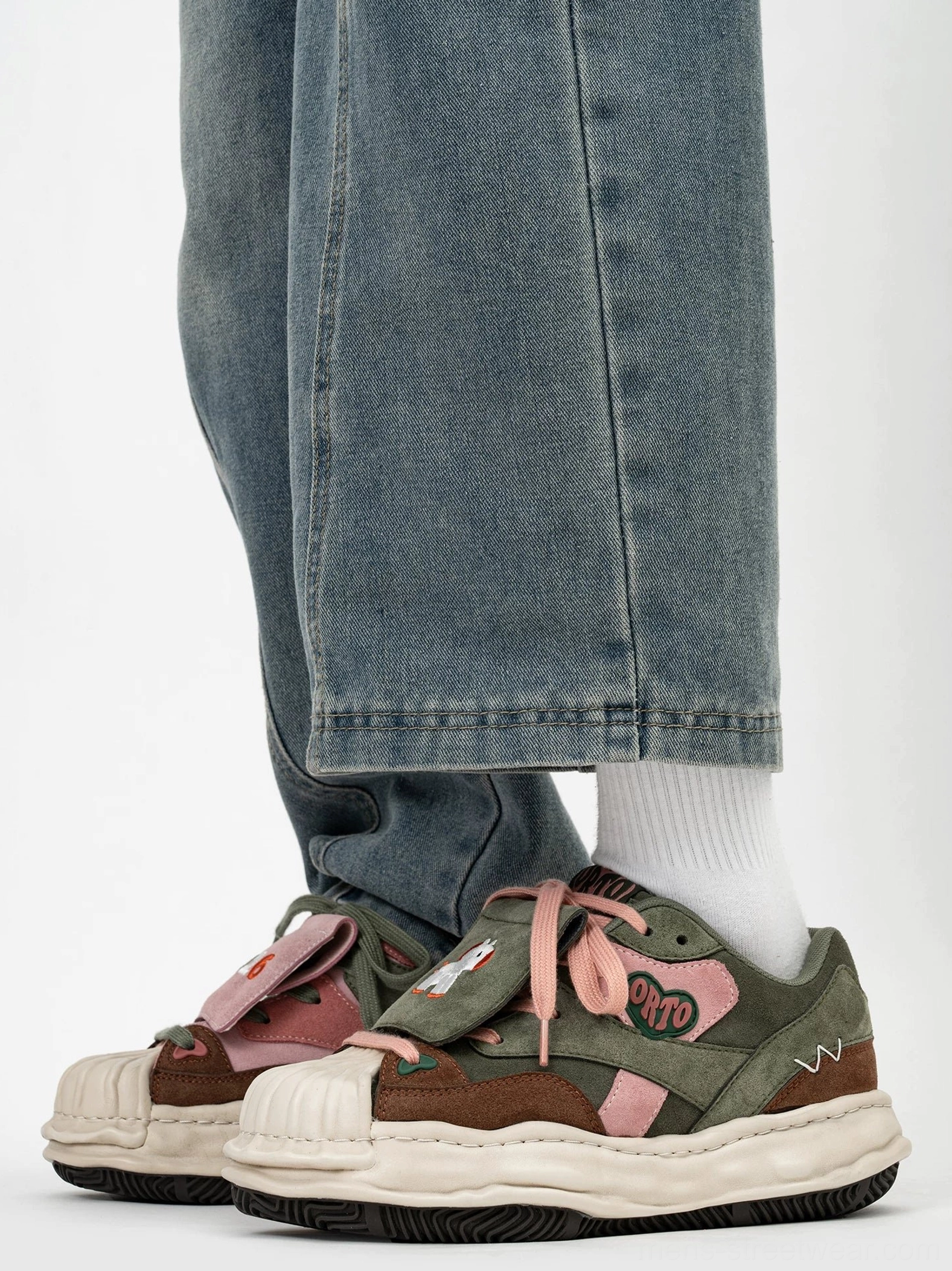 Worn view of playful patchwork shell-toe sneakers with contrasting horse and 2026 decorative patches and chunky cream sole