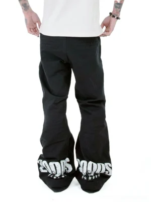 Rear full view of black Y2K 2000s graphic flare jeans showing bold white 2000S prints and star details on the wide hems