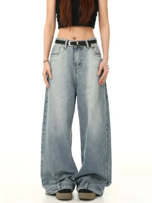 Female model wearing washed blue Y2K baggy wide-leg jeans in a full front view with black cropped tank top belt and casual shoes