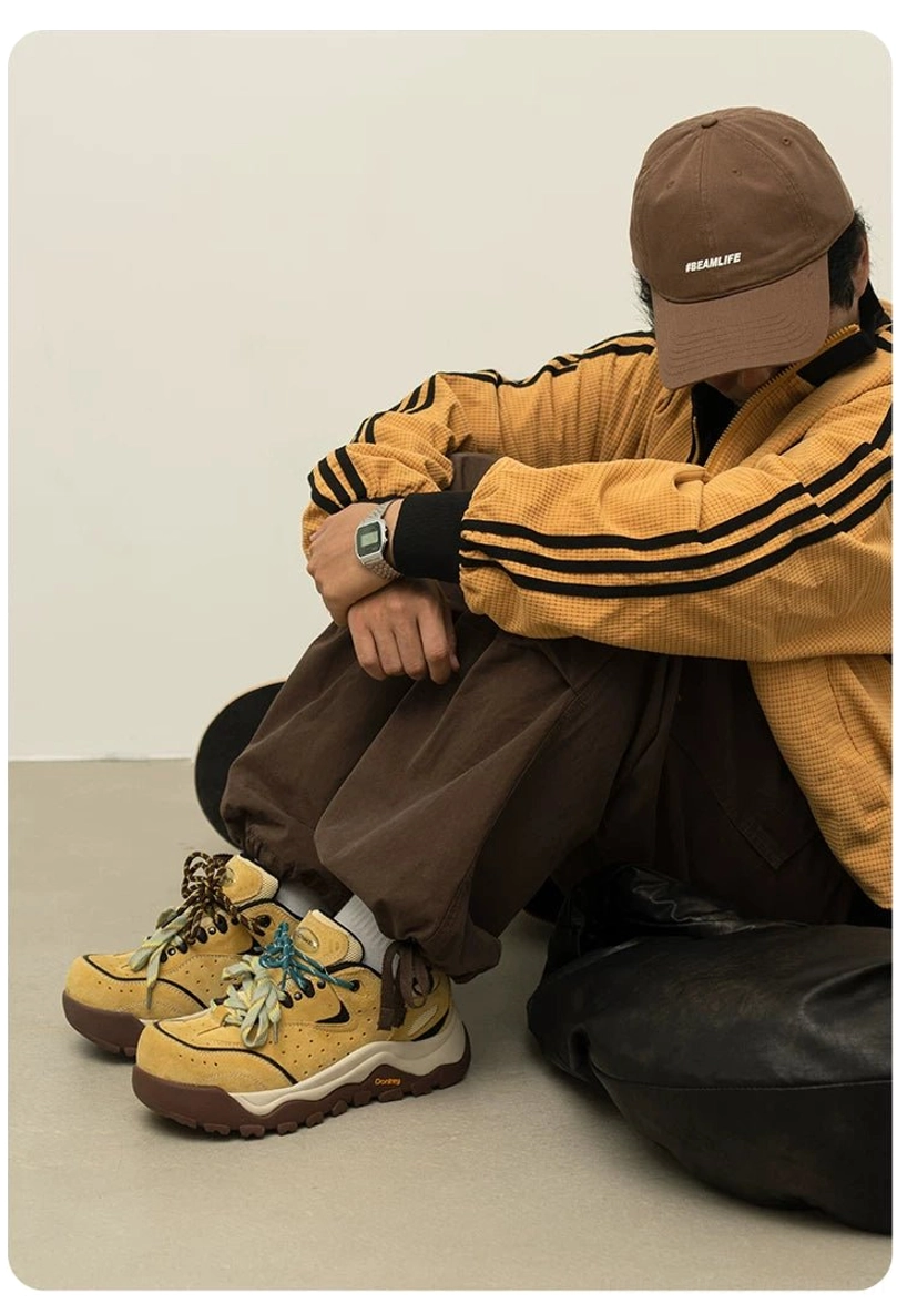 Yellow brown chunky trail sneakers shown from a low angle with track jacket and brown trousers, featuring the thick sculpted midsole and trail outsole
