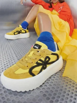 Yellow four-leaf chunky platform sneakers worn with a bright streetwear outfit in a low-angle close-up
