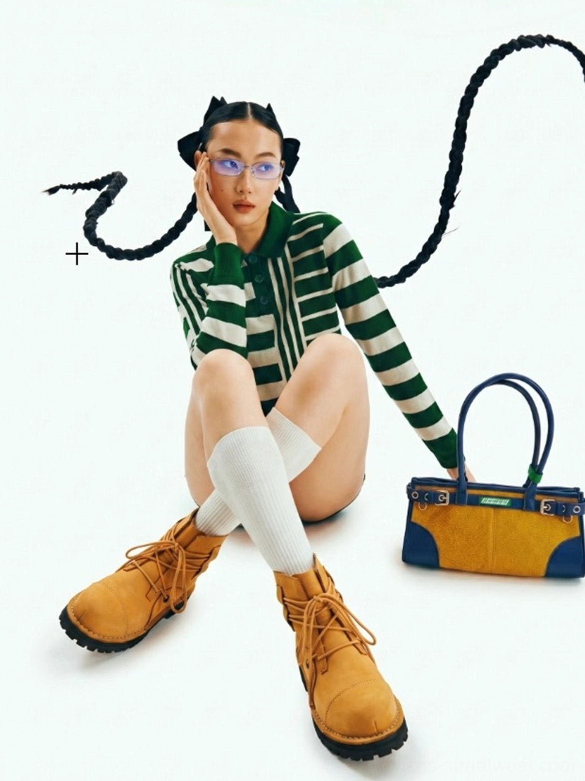 Female model styling yellow leather utility ankle boots with white socks and striped knit streetwear outfit