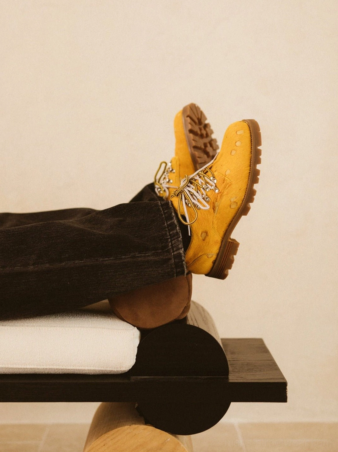 Rear angled view of mustard yellow spotted derby shoes worn with black jeans highlighting chunky treaded rubber outsole and lace details