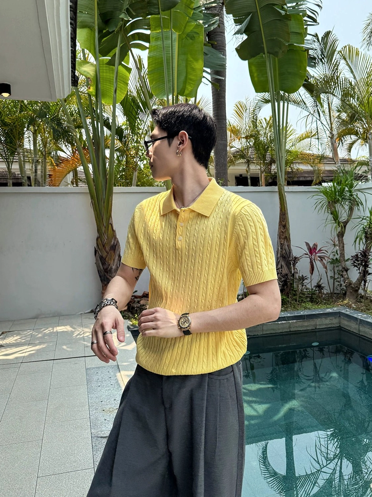 Yellow textured cable knit polo shirt in a tailored relaxed fit, styled by a male model at a sunny poolside resort