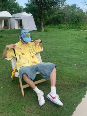 Yellow waffle embroidered floral short sleeve streetwear shirt with colorful flower embroidery worn in an outdoor lounge setting