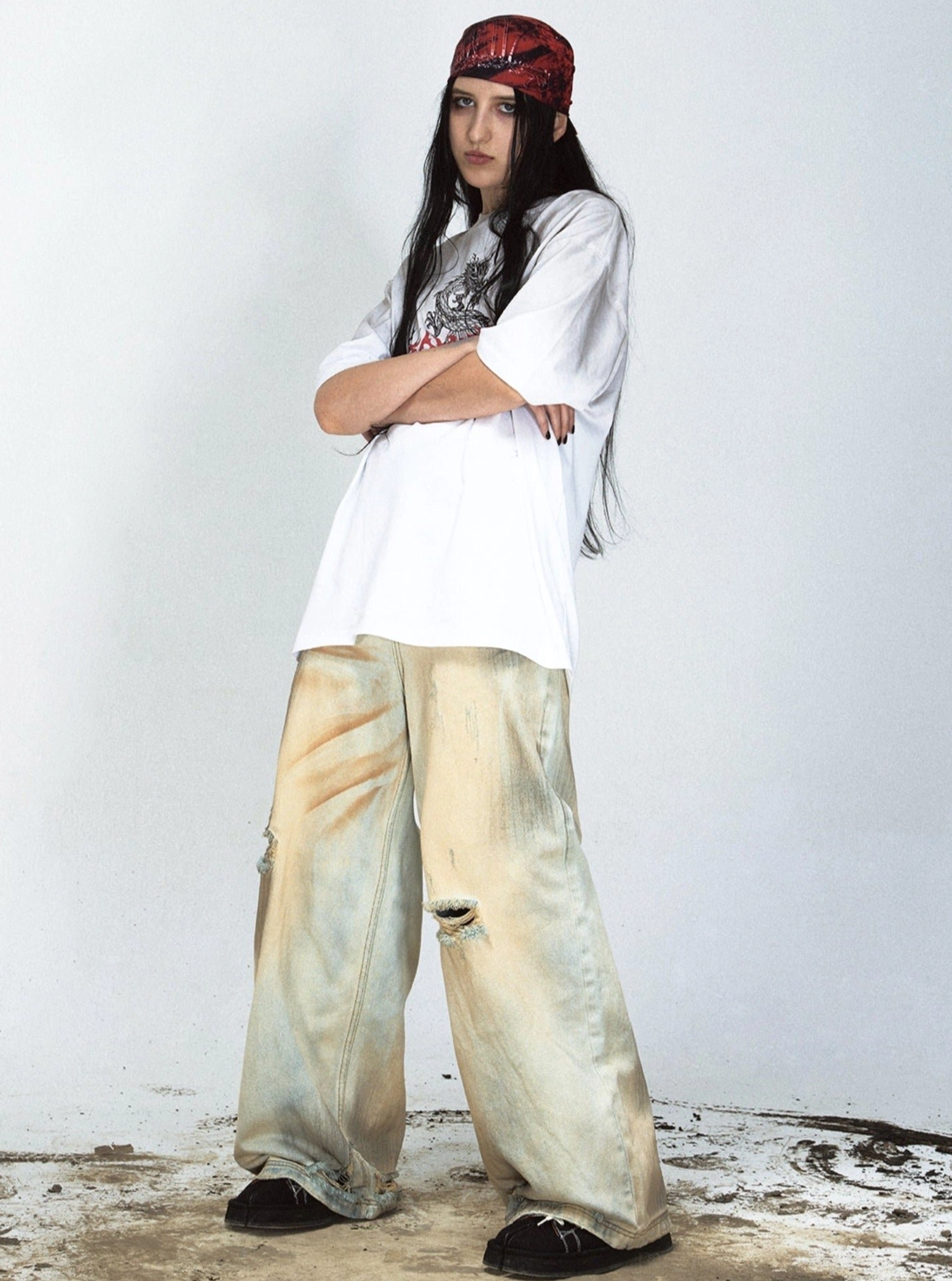Female model side view wearing loose yellow washed distressed denim jeans with oversized graphic shirt