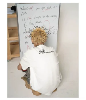 Rear low angle view of a white oversized graphic streetwear T-shirt with upper back typography print and relaxed short sleeve fit